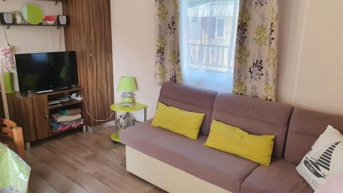 - un salon avec un canapé brun et des oreillers jaunes dans l'établissement Aux flamants rose, à Saint-Jean-de-Monts