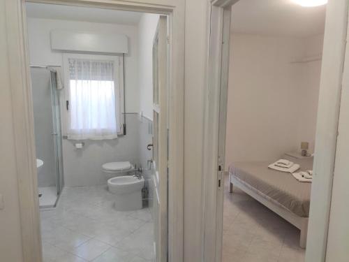 ein weißes Bad mit einem WC und einem Bett in der Unterkunft Cla House in Assemini