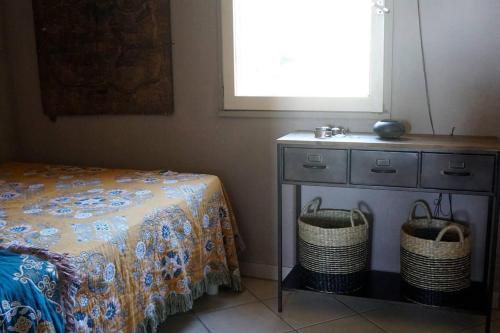 a bedroom with a bed and a dresser with two baskets at Lovely 1-Bed Apartment literally on the beach in Cerbère