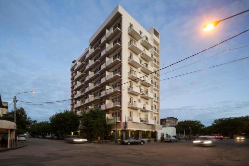 Hotel Tivoli Beira في بيرا: مبنى ابيض طويل على شارع المدينة وبه سيارات