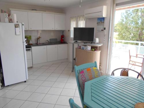 Il comprend une cuisine équipée d'un réfrigérateur, d'une table et d'une chaise. dans l'établissement Appartement T3 Climatisé - Terrasse Sud, Parking Privé, 6 Couchages - Le Grau-du-Roi - FR-1-250-218, au Grau-du-Roi