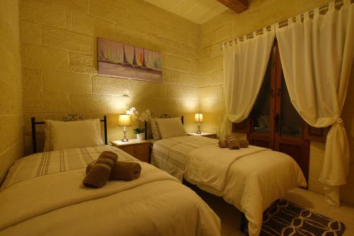 1 dormitorio con 2 camas y toallas. en Farmhouse Renee, en Qala