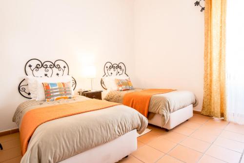 two beds in a room with orange and white at Betica Hotel Rural in Pias