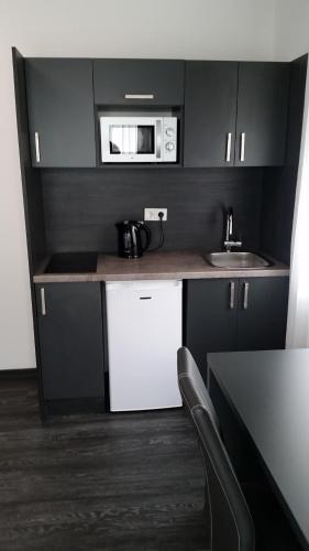 a small kitchen with a microwave and a sink at APPART-HOTEL, Einsteinstraße in Herzogenaurach