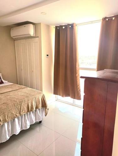 a bedroom with a bed and a window and a dresser at Bay Front Apt 208 in Portmore