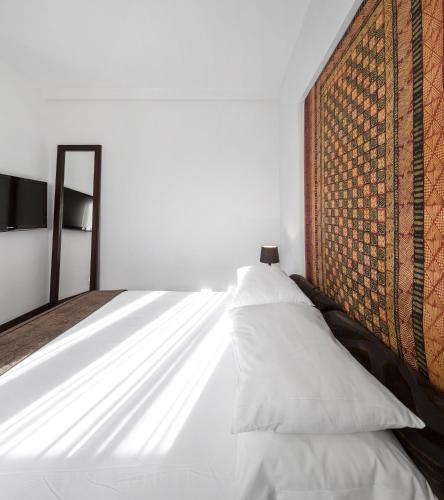 a bedroom with a bed with white sheets and a wall at Hotel Tivoli Beira in Beira