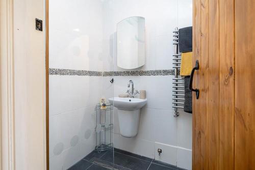 Baño blanco con lavabo y espejo en Red Robin Cottage en Gaerwen