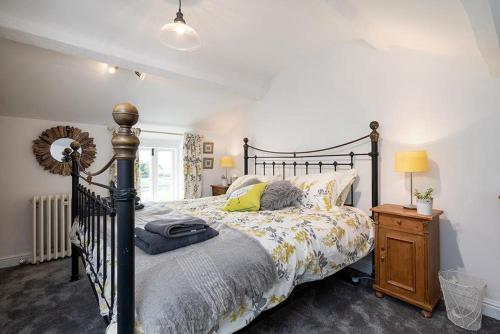 a bedroom with a bed and a wooden night stand at Red Robin Cottage in Gaerwen