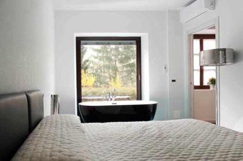 a bedroom with a bed and a tub and a window at Le Stanze Della Musica in Borgomale