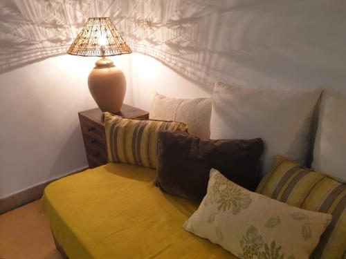 ein Wohnzimmer mit einem Sofa mit Kissen und einer Lampe in der Unterkunft RIAD EN EXCLUSIVITE SUITE MEDINA BY DO in Marrakesch