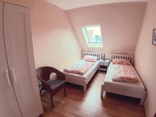 a room with two beds and a chair and a window at Haus Strandgang, Whg 4 in Kellenhusen