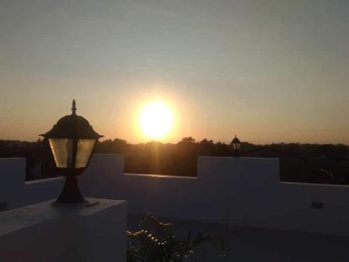 a sunset over a white building with a street light at Melvince Lodging House in Vigan