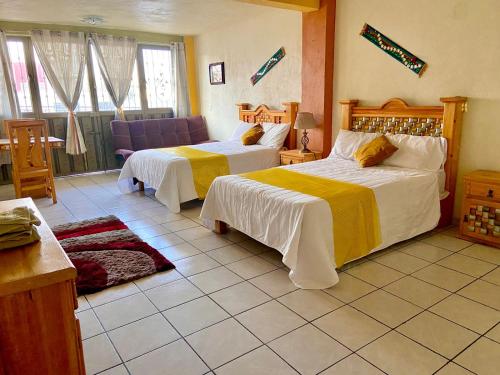 a hotel room with two beds and a couch at Hotel Carnaval in Huejotzingo