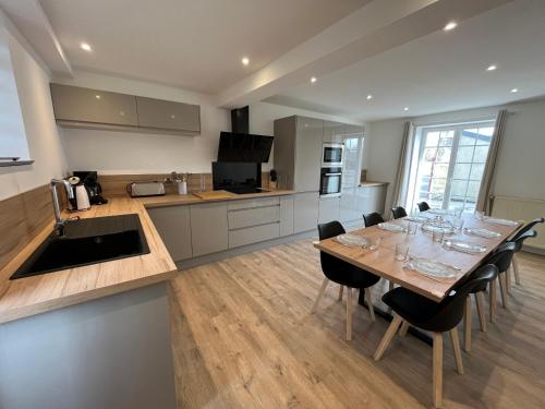 une cuisine avec une grande table en bois et des chaises dans l'établissement Etanin, Maison entièrement rénové proche mer et ville, à Bény-sur-Mer