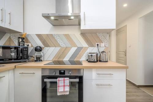 a kitchen with white cabinets and a stove top oven at L'écrin authentique in Audincourt