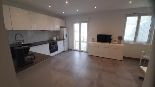 a large kitchen with white cabinets and a television at Calvi, T3, vue mer, grande terrasse in Calvi