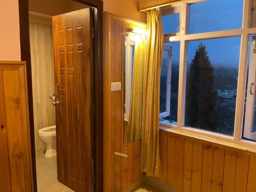 an open door to a bathroom with a toilet and a window at Montanamar Lachung in Lachung