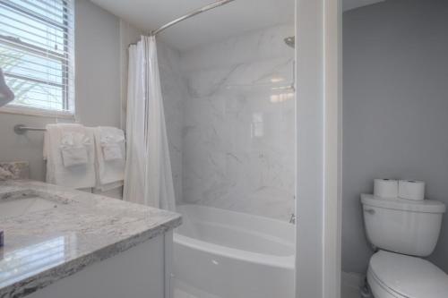 a white bathroom with a shower and a toilet at Shore To Please Beach Oceanfront Patio Pet Friendly in Jacksonville Beach