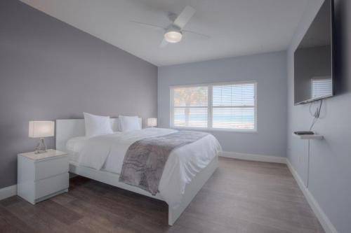 a white bedroom with a bed and a window at Shore To Please Beach Oceanfront Patio Pet Friendly in Jacksonville Beach