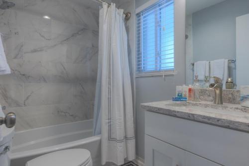a bathroom with a shower and a toilet and a sink at A Wave From It All Oceanview 2nd Level Patio in Jacksonville Beach