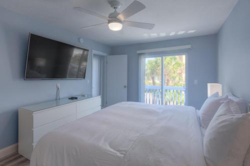a bedroom with a white bed with a flat screen tv at Sandy Feet Retreat 4 Oceanview Balconies Pets Ok in Jacksonville Beach