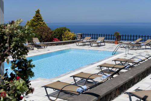 a swimming pool with chaise lounges and chairs at Anthonas Apartments in Imerovigli