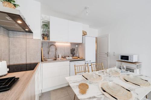 une cuisine avec des placards blancs et une table avec des assiettes. dans l'établissement Le Bohème - Charming apartment in the city centre, à Annecy