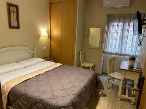 a hotel room with a bed and a desk and a window at Hostal Toledo Plaza in Toledo