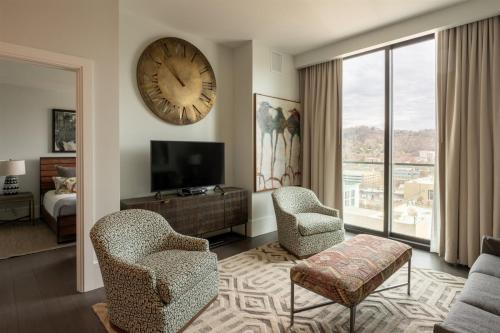 a living room with a large clock on the wall at 'The Views Over Pack Square Park' A Luxury Downtown Condo with Mountain and City Views at Arras Vacation Rentals in Asheville