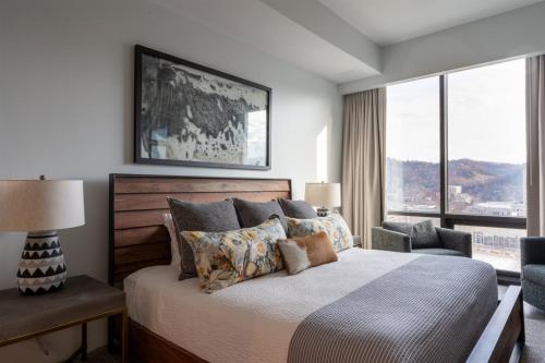 a bedroom with a bed and a large window at 'The Views Over Pack Square Park' A Luxury Downtown Condo with Mountain and City Views at Arras Vacation Rentals in Asheville