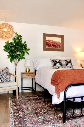 1 dormitorio con cama, planta y silla en Kinnikinnik Motor Lodge, en Estes Park