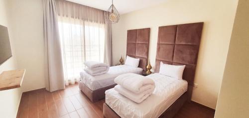 una camera con due letti con lenzuola bianche e una finestra di COSY APPART avec 2 piscines, 2 CH, 2 SDB Marrakech a Marrakech