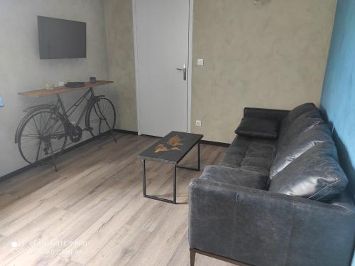 a living room with a couch and a table and a bike at Apparts'hôtel la ferme du gros noyer in Malaucène