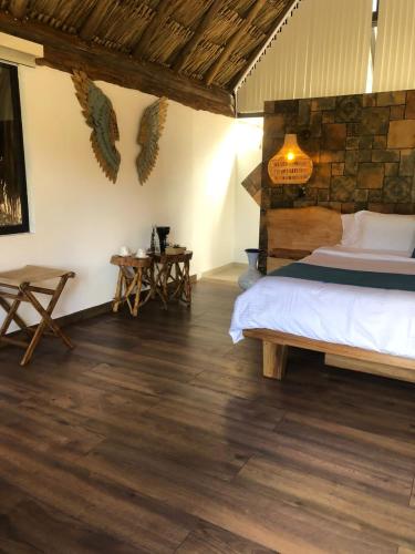 a bedroom with a bed and wooden floors at Rancho Ecoturistico el Faro in La Mesa