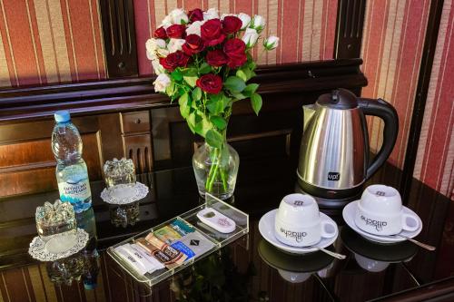 Tiso Apart Hotel في كييف: طاولة مع إناء من الورد ومجموعة من الشاي