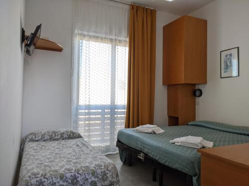 a bedroom with two beds and a window at Albergo casa del turista in Torre dell'Orso