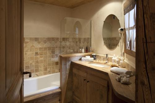 La salle de bains est pourvue d'un lavabo, d'une baignoire et d'un miroir. dans l'établissement Chalet-Hôtel Les Fermes de Pierre & Anna, au Grand-Bornand