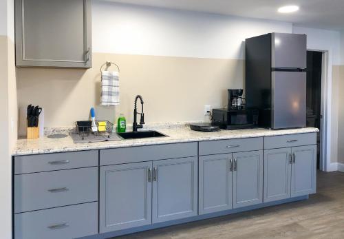 a kitchen with white cabinets and a stainless steel refrigerator at Lazy Cuckoo Inn - Sleek and Stylish Studio Apartments in Fort Myers Beach