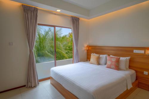 a bedroom with a bed and a large window at Niru Isle Maldives in Gaafaru