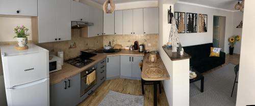 a small kitchen with white cabinets and a table at Domek nad potokiem in Kluszkowce