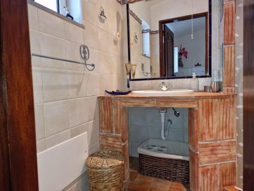a bathroom with a sink and a mirror and a tub at Casa as Origens in São João dos Caldeireiros