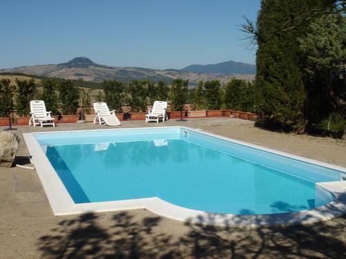 a swimming pool with two lawn chairs and two lawn chairs at Agriturismo Podere dei Venti in Piancastagnaio