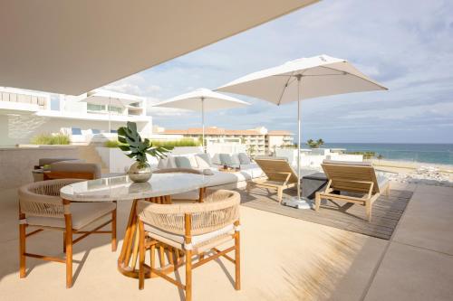 patio ze stołem, krzesłami i parasolem w obiekcie Viceroy Los Cabos w mieście San José del Cabo