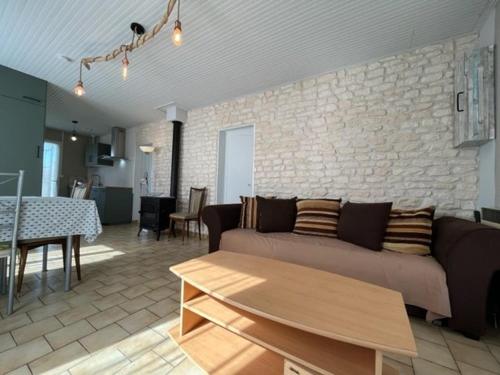 un salon avec un canapé et un mur en pierre dans l'établissement Maison proche plage et pistes cyclables, 6 couchages, jardin clos, parking, ménage inclus - Saint-Denis-d'Oléron - FR-1-246A-190, à Saint-Denis-dʼOléron