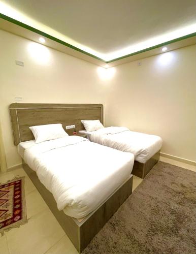 two beds in a hotel room with white sheets at RoadHouse - Petra in Wadi Musa