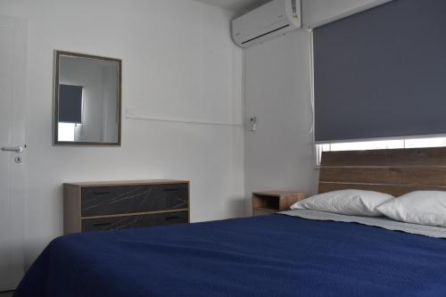 a bedroom with a blue bed and a mirror at Maria Holiday Apartments in Protaras