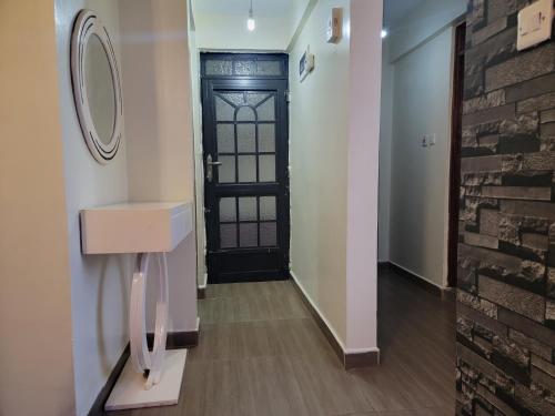 un pasillo con una puerta negra y un espejo en Sweet Homes Apartment Near all Embassies en Ruaka