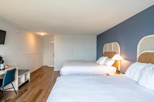a hotel room with two beds and a desk and a table at Seagull Beachfront Inn in Lincoln City