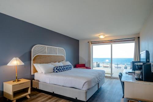 Schlafzimmer mit einem Bett, einem Schreibtisch und einem Fenster in der Unterkunft Seagull Beachfront Inn in Lincoln City