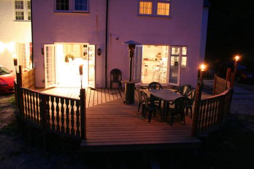 a wooden deck with a table and chairs on it at Oakhurst Gatwick B&B in Crawley